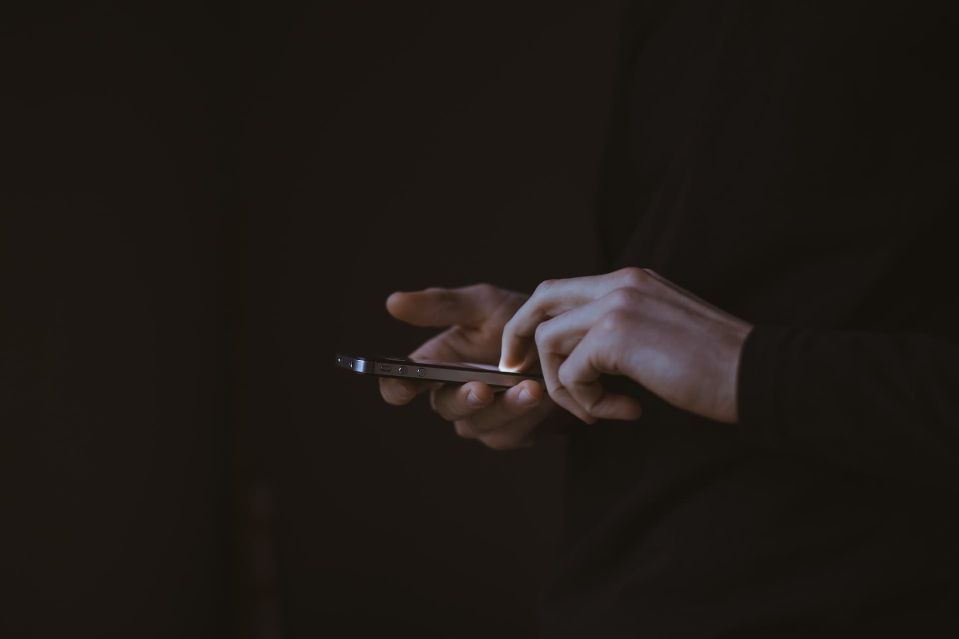 Hands holding a phone in low light